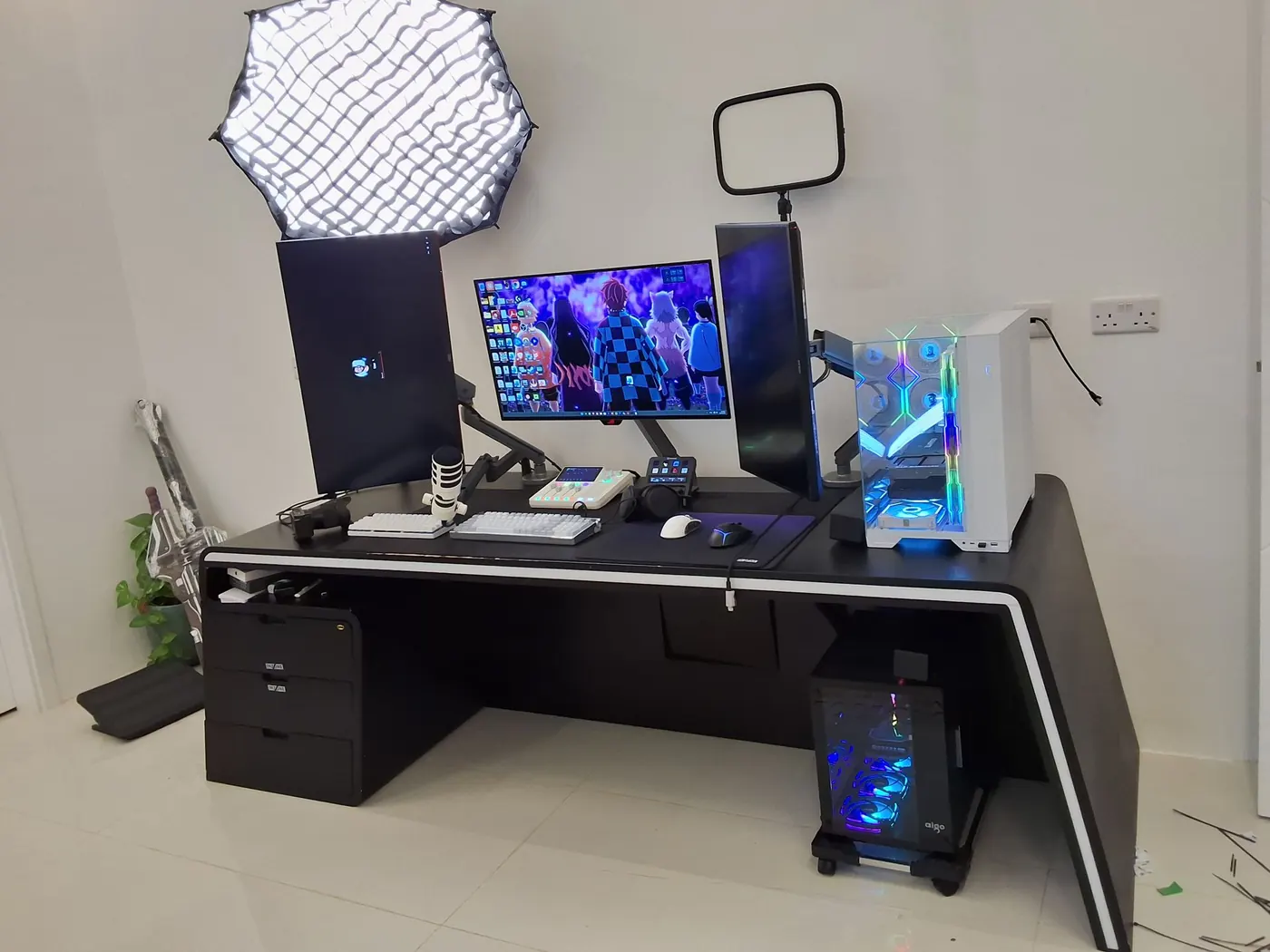 Triple-monitor creator desk: the cable nest gone from the floor, the tower lit — after
