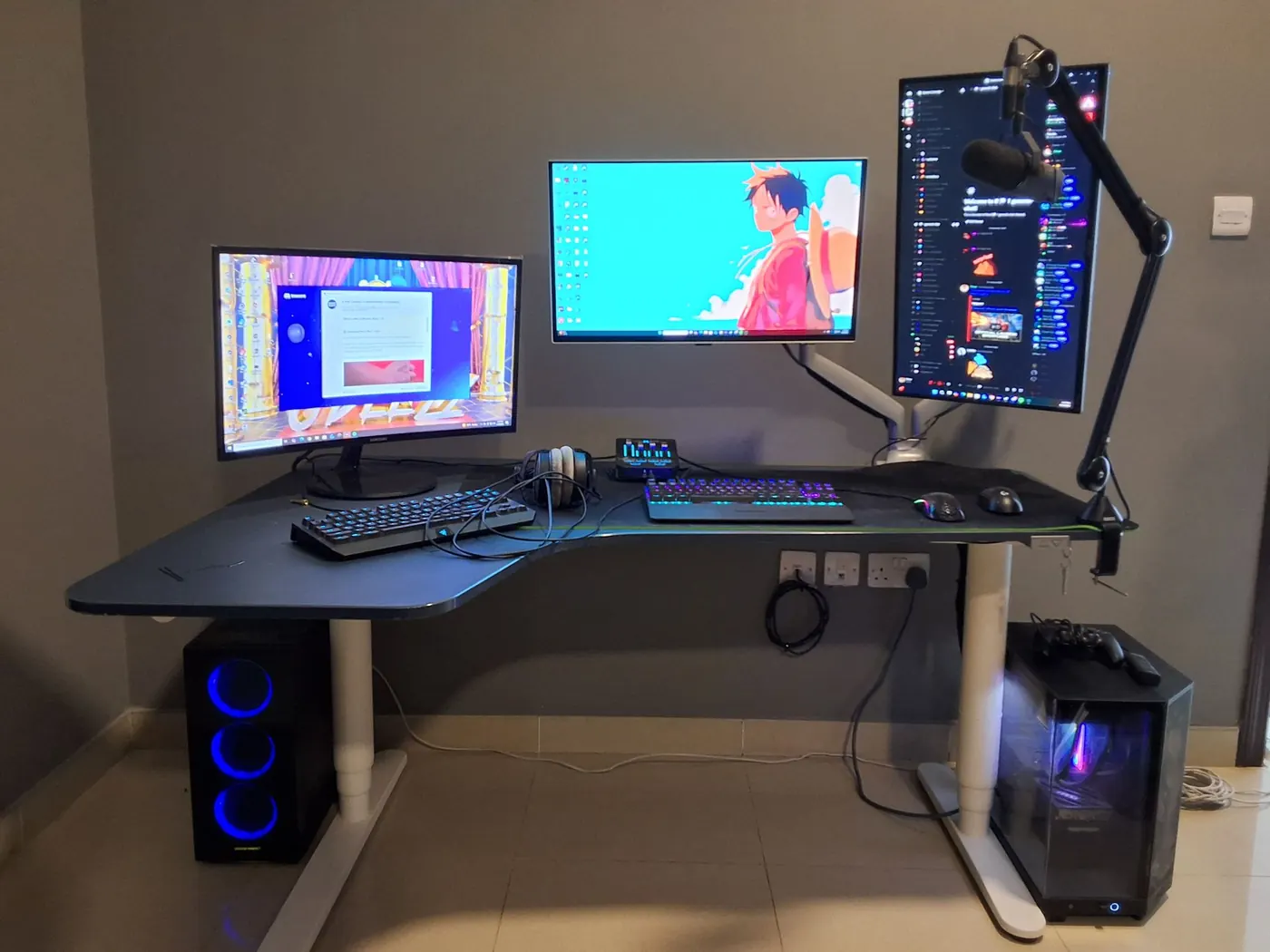 Corner battle station: mic arm, three screens and two towers, all cabled clean — after