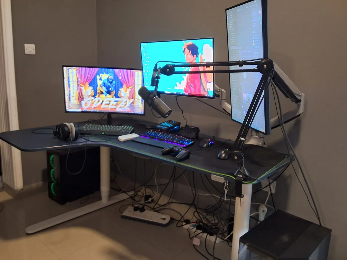 Corner battle station: mic arm, three screens and two towers, all cabled clean — before